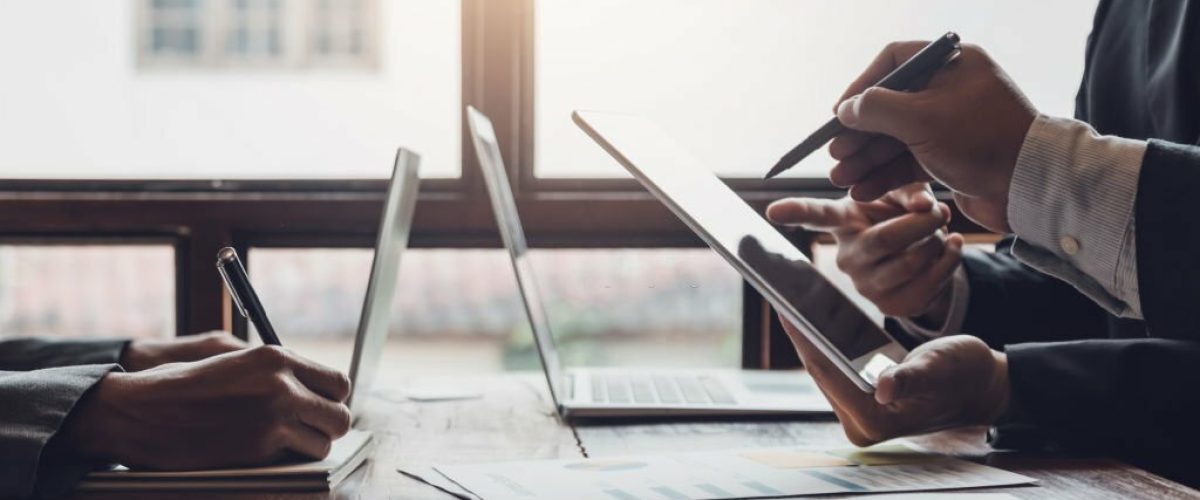 Group of business people meeting, discussing, analyzing graphs, financial data, and planning a marketing project together.